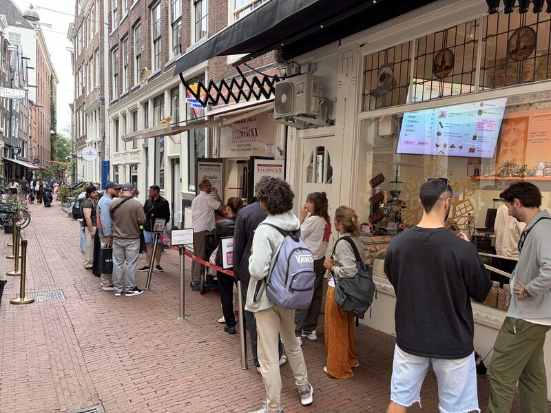 The queue behind Vleminckx-red ribbons stretching down Voetboogstraat, past The Dutch Chocolate Bar